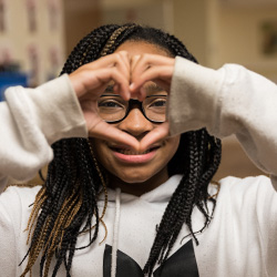 School-age child making heart shape with hands and smiling