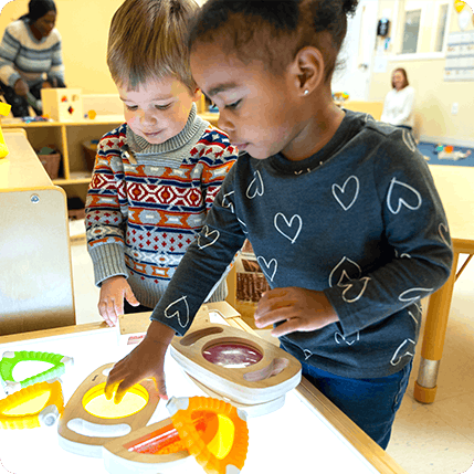 two preschool students learning at a light table