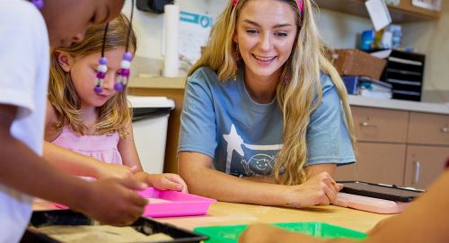 Teacher smiling as children participate in a hands-on classroom activity