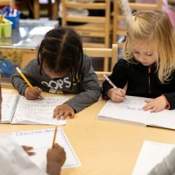 Niños escribiendo juntos durante una actividad de aprendizaje en grupos pequeños