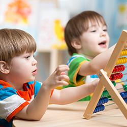 Niños de preescolar explorando cómo contar cuentas en ábaco en la mesa del aula
