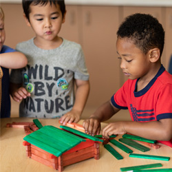 Boys building cabin our of wooden block pieces