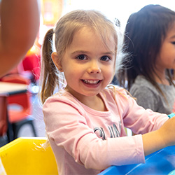 niña sonriendo en la mesa del aula