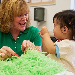 Teacher supporting child during sensory play activity with textured materials