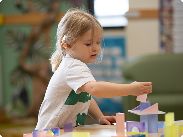 Young child building with blocks at classroom table